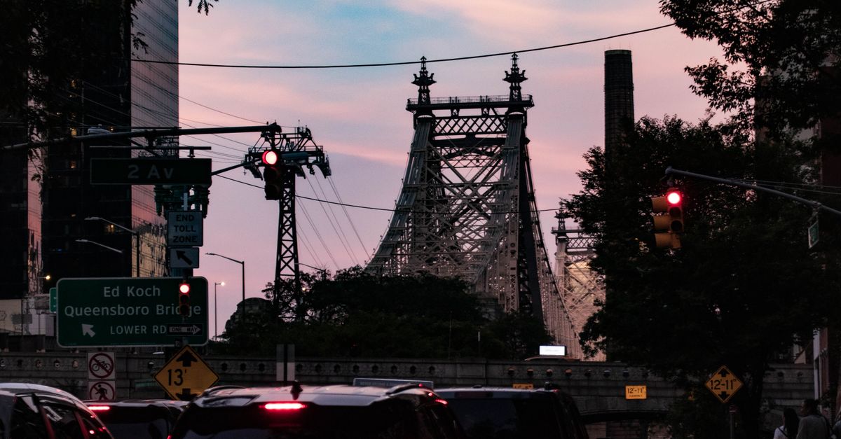 Traffic and skyline view of Ed Koch Queensboro Bridge at sunset with vibrant sky.